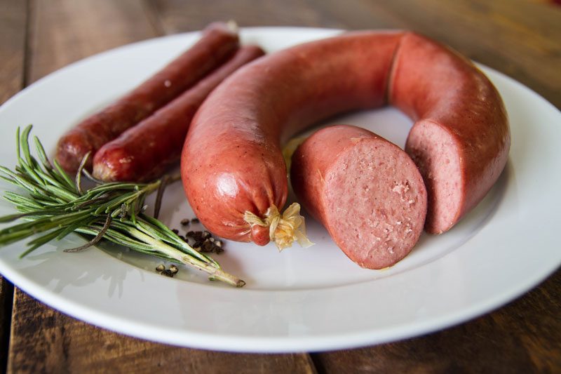 Two types of sausages arranged on a plate with some herbs
